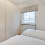 Schlafzimmer mit Bett, Kleiderschrank und Fenster mit Rollladen.