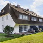 Haus mit strohgedecktem Dach, weißer Fassade und großem Garten.