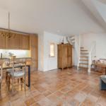 Küche mit Esstisch, Wohnbereich mit Sofa und Holztreppe zur Galerie.