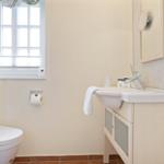 Bathroom with sink, mirror, toilet, and window.