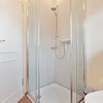 Shower with glass enclosure, toilet, and sink in bathroom