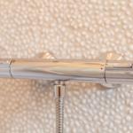 Chrome shower mixer with temperature display on textured wall panel