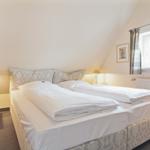 Bedroom with double bed, nightstand, and window with curtains.