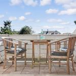 Terrace with table and two chairs, view of sky and trees.