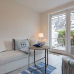 Wohnzimmer mit Sofa, Tisch und Blick auf Balkon