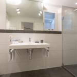 Badezimmer mit Waschbecken, Spiegel und Dusche