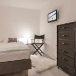 Schlafzimmer mit Bett, Kleiderschrank und Fernseher an der Wand.