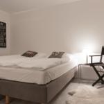 Schlafzimmer mit Bett, Nachttisch, Stuhl und Wandbild.