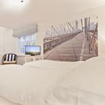 Schlafzimmer mit großem Bett, Wandbild einer Brücke und Fenster mit Vorhang.