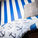 Sofa mit blau-weiß gestreiftem Bezug und Anker-Motiv-Kissen und Decke.
