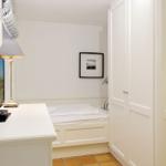 Schlafzimmer mit Bett, Schrank und TV-Tisch. Wandbild und Lampe sichtbar.