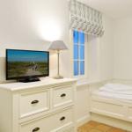 Schlafzimmer mit Bett, Schrank und Fernseher an der Wand.