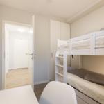 Zimmer mit Doppelstockbett, Schrank und Fernseher an der Wand.