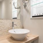 Waschbecken auf Holzplatte mit Steinwand und Spiegel