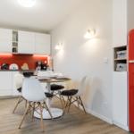 Küche mit Essbereich, roter Kühlschrank und weißen Schränken.