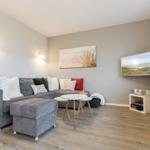 Wohnzimmer mit grauem Sofa, kleinem Tisch und Wandbild