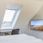 Bedroom with skylight, desk, and wall-mounted TV.