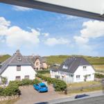 Wide view of houses with roofs and green slopes under blue sky.