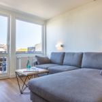 Living room with gray sofa, table, and large windows to balcony.