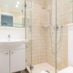 Badezimmer mit Dusche, Waschbecken und Spiegel