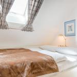 Schlafzimmer mit Dachfenster, Bett und Nachttischlampe.