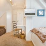 Schlafzimmer mit Bett, Sofa, Schreibtisch und Fernseher an der Wand.