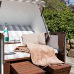 Strandkörbe mit Decke, Kissen und Getränk im Garten.