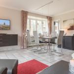 Living and dining area with TV, table and chairs, windows and curtains.