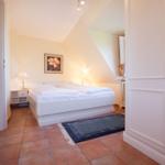 Bedroom with sloped ceiling, white bed, and tiled floor
