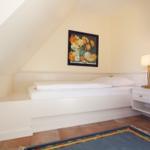 Bedroom with sloped ceiling, bed, nightstand, and wall art.