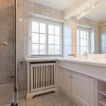 Bathroom with shower tub, window, and sink with mirror.