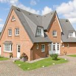 Red brick house with gray roof and white windows on green lawn.
