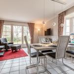 Dining area with six chairs and dining table. Living area with seating and red rug.
