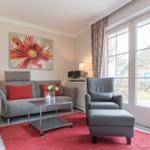 Living room with gray sofa, red rug, and large window.