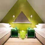 Zwei Betten mit Nachttischen und grüner Wand im Dachgeschosszimmer.