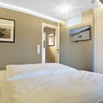 Schlafzimmer mit Bett, Wandbild und Fernseher an der Wand