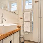 Badezimmer mit Waschbecken, Spiegel, Handtuchhalter und Dusche.