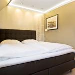 Schlafzimmer mit Doppelbett, Wandbild und Stehlampe.