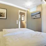 Schlafzimmer mit Bett, Wandbild und TV. Hintergrund: Tür und Kleiderschrank.