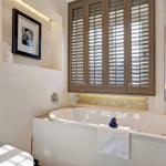Bad mit Badewanne, Fenster mit Jalousien und Handtuchhalter.