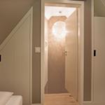 Schlafzimmer mit Dachschrägen und integriertem Schrank. Durchgang zur hängenden Lampe.