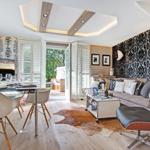 Wohn- und Essbereich mit Sofa, Tisch und Stühlen. Hintergrund mit Tapete und Fenster zur Terrasse.