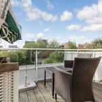 Terrace with wicker furniture and view of green areas and houses