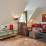 Living room with red sofa, armchair, and wooden table under sloped walls.