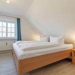 Bedroom with double bed, nightstand, and window with curtains.