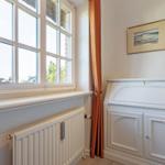 Room with window, radiator, and white cabinets.