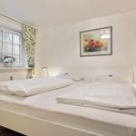 Bedroom with white bed, window with floral curtains, and wall art with poppies.