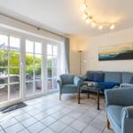 Living room with sofa, armchair, and terrace. Windows with gray curtains.