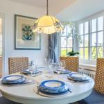Round table with chairs, floral decor, and window view.