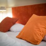 Bed headboard in orange with pillows on bed
